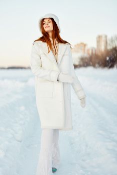 beautiful woman in a white coat in a hat winter landscape walk Lifestyle. High quality photo