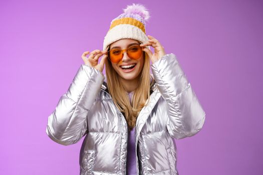 Good-looking charming happy smiling blond girlfriend having fun vacation girlfriends put on sunglasses grinning delighted wear cool silver glittering jacket warm winter hat, purple background.