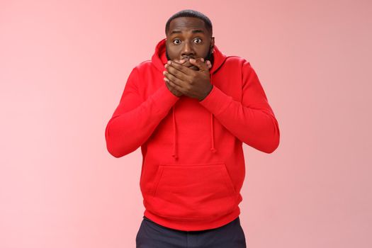 Shocked gasping surprised african-american guy overhear stunning rumour press palms mouth not slip word widen eyes impressed stunned unbeliavable amazing gossip, standing pink background.