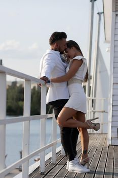 Loving couple hugging while standing on embankment near boats on sunny day in summer