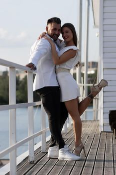 Loving couple hugging while standing on embankment near boats on sunny day in summer