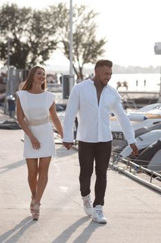 Loving couple hugging while standing on embankment near boats on sunny day in summer