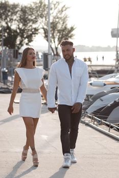 Loving couple hugging while standing on embankment near boats on sunny day in summer