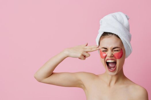 portrait woman pink patches on the face with a towel on the head pink background. High quality photo