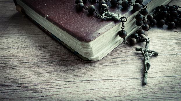 Holy Bible and Holy Rosary on wooden desk. Religious concept