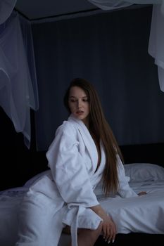 From above of topless sexy female in bathrobe lying on comfortable bed in bedroom
