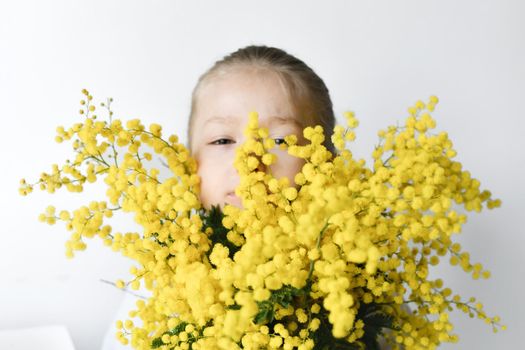 A girl holding mimosa on a white wall background