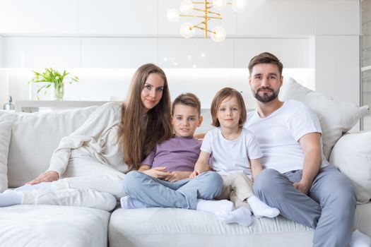 Happy family of parents with children sitting together on sofa at home