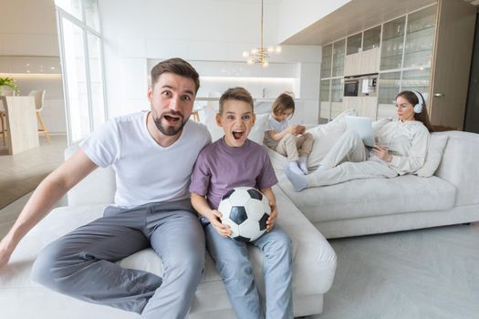 Family having fun at home father and son soccer fans cheering sports, mother and daugher playing anbd listening music