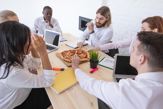 Diverse business team people workers eating pizza together at workplace, friendly multi-ethnic colleagues group talking enjoying having fun and corporate lunch in office room