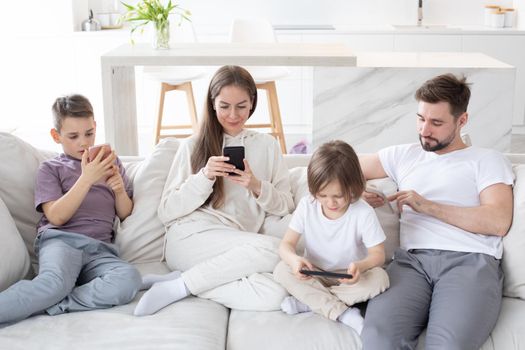 Portrait of family with two kids having holding smart phone electronic device in hands texting sms using wi-fi 5G internet checking email searching contact. Apps concept