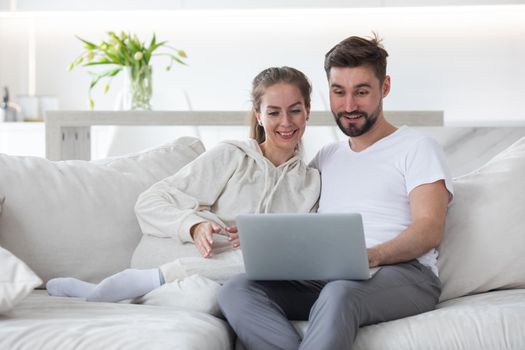 Happy married couple spending free leisure weekend holiday time with laptop indoors.