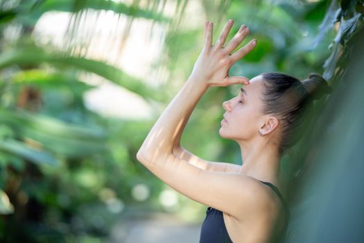Female meditating and practicing yoga in tropical rainforest. Beautiful young woman practicing yoga outdoor with tropical forest in background