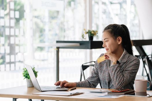 Happy asian woman hands holding credit card and using laptop computer. Online shopping concept