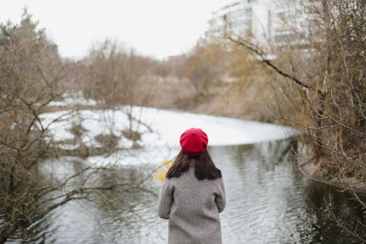 Woman wearing a red hat photographed from behind while looking on the frozen winter lake outdoors