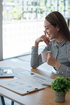 Portrait asian business woman analyzing statistics financial by paperwork and video call with her business team