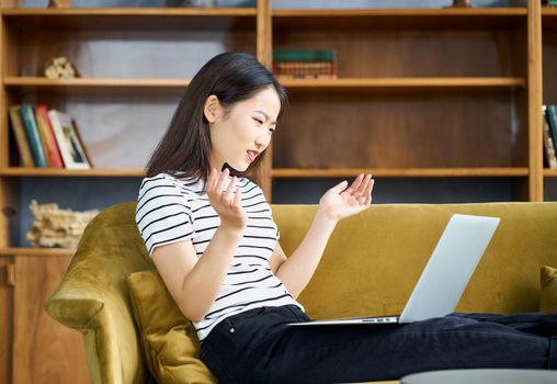 Asian girl throwing up hands in surprise, gesture of indignation. Woman looking shock at laptop unexpected news and is outraging