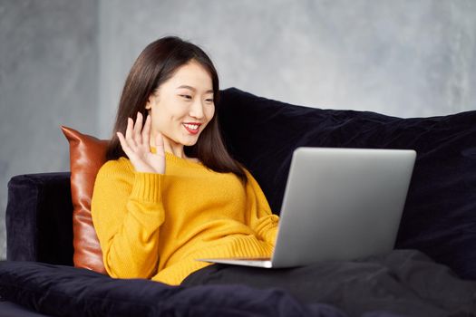 Asian woman waving hands looking to laptop. Online dating, meeting with friends, Live chat, stream. Girl with long hair, freelancer, blogger. Good luck concept, positive communication.