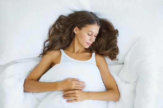 Top view waist portrait of beautiful sleeping woman in bed. Female with long hair resting, good night sleep concept, enjoying fresh soft bedding linen and mattress in bedroom