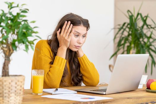 Girl surprising, upset and offended. Beautiful young woman working at laptop in workplace at home, sadden emotion