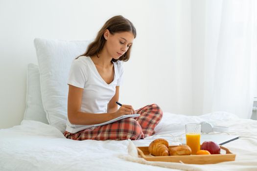 Morning pages, stream of consciousness journaling habit, first thing every morning on daily basis. Woman waking up, opening morning journal and writing three pages