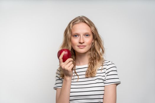 Portrait of young smiling woman with red apple. Fresh face, natural beauty, realistic. Clean young fresh skin without makeup and retouching. Healthy care