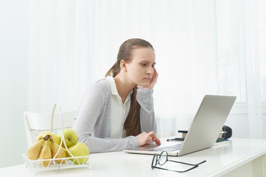 Distance education for students. Quarantine, self-isolation, sociophobia. Young girl listens to online learning, teleworking, online lectures.Woman look at laptop. Freelancer, Digital Nomad Concept