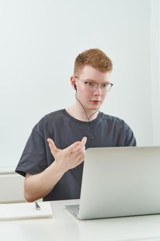 Distance learning or working. Quarantine, self-isolation, social phobia. Young boy speaking on online training, telework. Man looks at laptop. Freelancer, Concept Of Digital Nomad