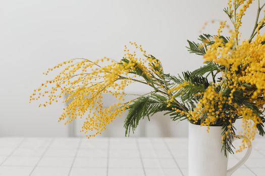 Spring flowers composition. Yellow mimosa flowers on white background in home interior.
