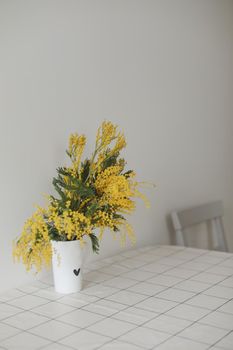 Mimosa branches in a glass vase on the table.