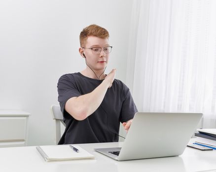 Distance learning or working. Quarantine, self-isolation, social phobia. Young boy speaking on online training, meeting, conference. Man looks at laptop. Freelancer, Concept Of Digital Nomad