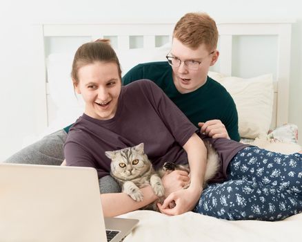 Teen in love lying on bed, watch movies on laptop during quarantine due to coronavirus pandemic. Boy and girl relaxing while staying at home. Concept of self-isolation, sociophobia