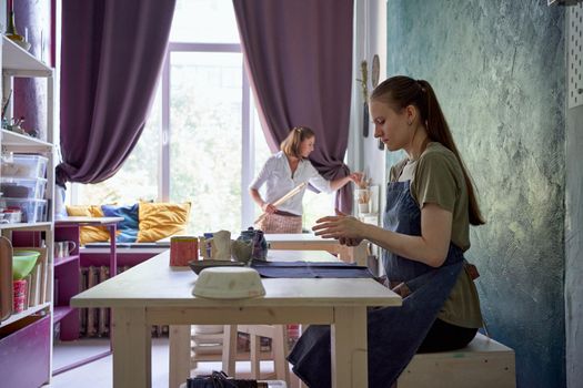 Woman making ceramic pot on workshop. Concept for woman in freelance, business. Handcraft product. Teacher trainsstudent, master instructs apprentice