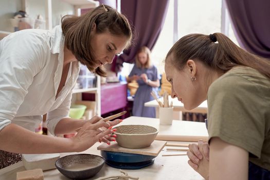 Woman making ceramic pot on workshop. Concept for woman with hobbys. Handcraft product. Teacher trainsstudent, workshop