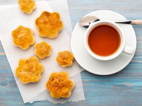 traditional breakfast with a cup of tea and sweet pastries. A plate of scones, a mug of tea, spoon on wooden blue table, top view, rustic style.