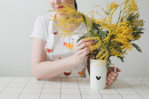 Beautiful young smiling woman with mimosa flowers on white background.