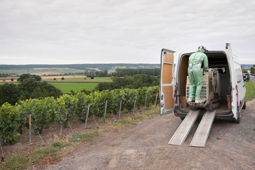 worker in protective clothing finished spraying vines in champagne vineyard near marne valley south of reims in france