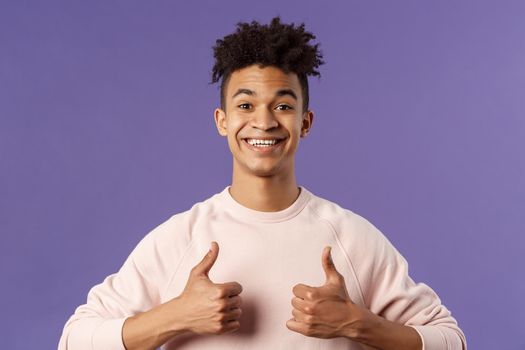 Close-up portrait of enthusiastic handsome young teenage guy, college student recommend awesome courses, online education school, show thumbs-up as recommending, like and approve, smiling.