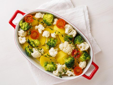 Dietary vegetarian dish of raw mixed vegetables - potatoes, cauliflower, broccoli, tomatoes, thyme, seasonings. Healthy diet. Top view, empty space for the test.