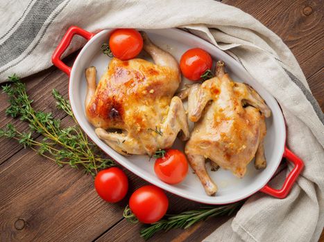 two carcasses fried chicken in a bowl, baked chucks in an oven with tomatoes, with crispy crust, on dark brown wooden rustic table, top view