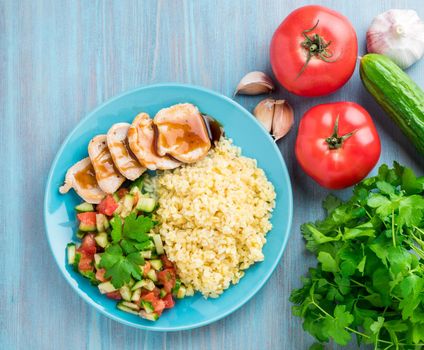 Turkey meat, fried with teriyaki sauce, cucumber salad tomato, vegetables, a side dish of bulgur, top view