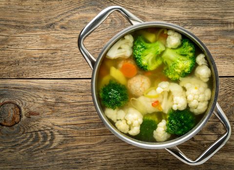 large metal pan with delicious hot soup of vegetables and meatballs, cauliflower, broccoli, carrots, peppers, potatoes, healthy diet food, top view, copy space