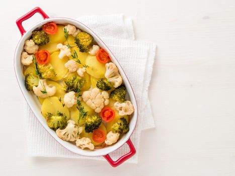 Dietary vegetarian dish of baked mixed vegetables - potatoes, cauliflower, broccoli, tomatoes, thyme, seasonings. Healthy diet. Top view, empty space for the test.