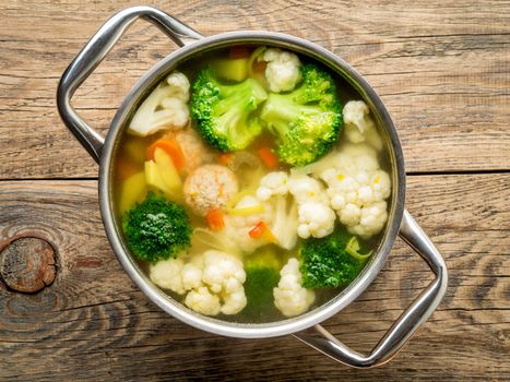 large metal pan with delicious hot soup of vegetables and meatballs, cauliflower, broccoli, carrots, peppers, potatoes, healthy diet food, top view