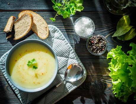 Dietary vegetarian cream soup puree, with potatoes and cauliflower, on a dark brown-blue wooden table, top view.