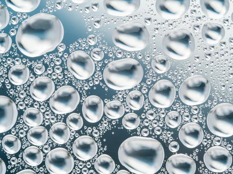 Abstract gray background with large and small spherical convex drops of water on glass. Bubbles on window. Macro, close up.