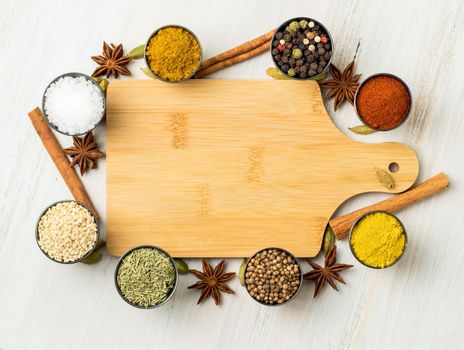 Various Indian spices in metal cups. Empty wooden Board, seasoning on white wooden table. top view, space for text.