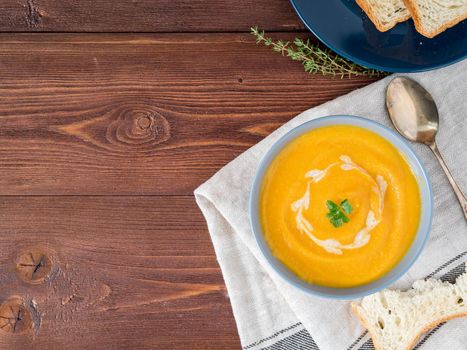 Dietary vegetarian pupmkin cream soup puree, on dark brown wooden table, top view, copy space, close up.