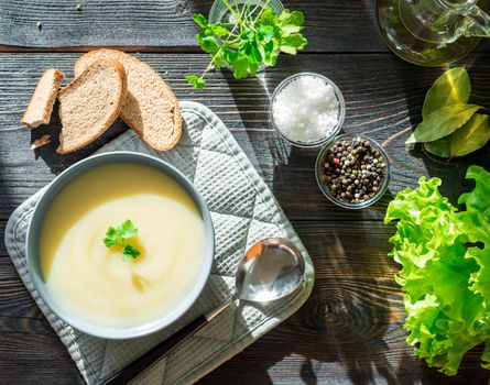 Dietary vegetarian cream soup puree, with potatoes and cauliflower, on a dark brown-blue wooden table, top view.