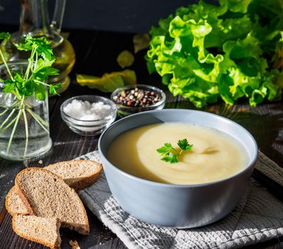 Dietary vegetarian cream soup puree, with potatoes and cauliflower, on a dark brown-blue wooden table, side view, close up